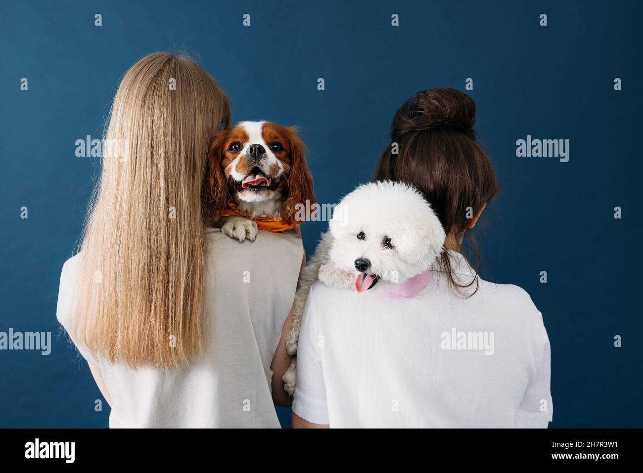Back view of two women standing with their dogs. Portrait of two little