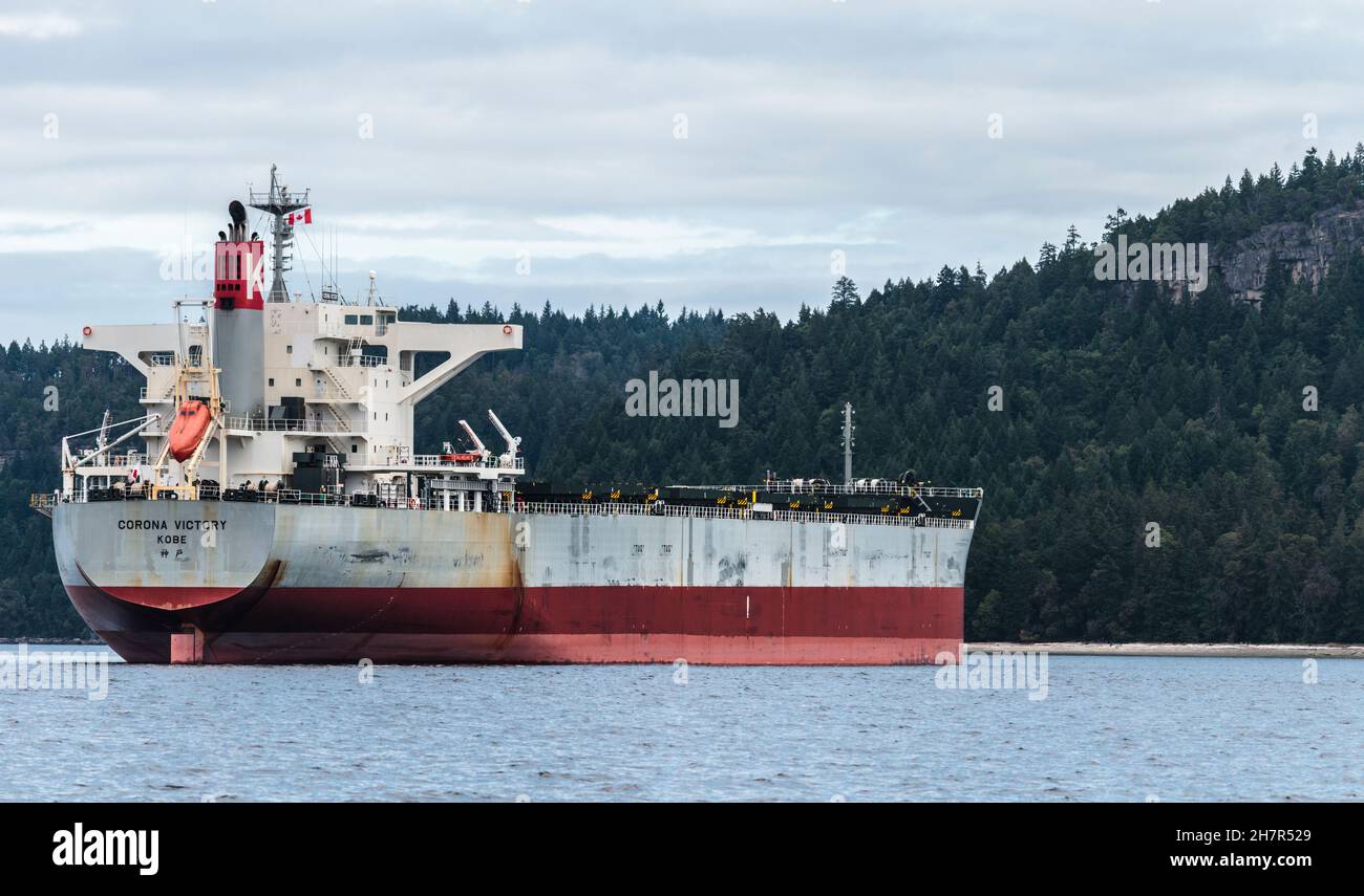 Sea level, stern quarter view of one of the many giant freighters anchored in BC's Gulf Islands, waiting to access the Port of Vancouver. Stock Photo