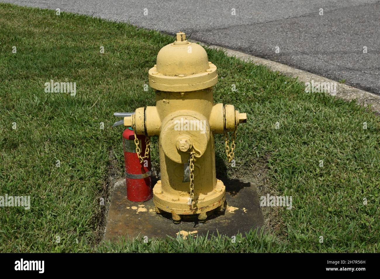An old fire hydrant is near a portable extinguisher. Stock Photo