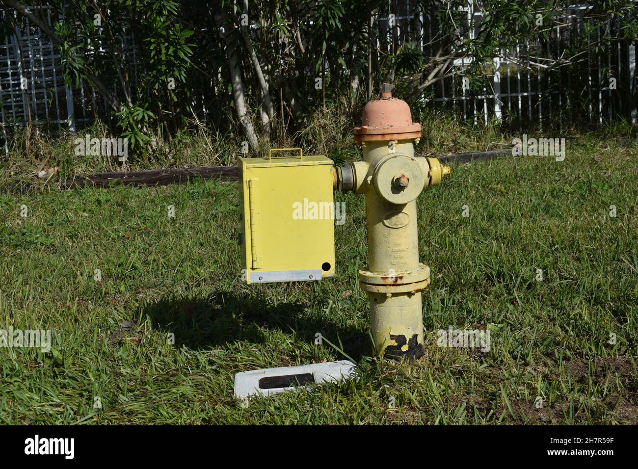 A yellow box attached to an old fire hydrant. Stock Photo