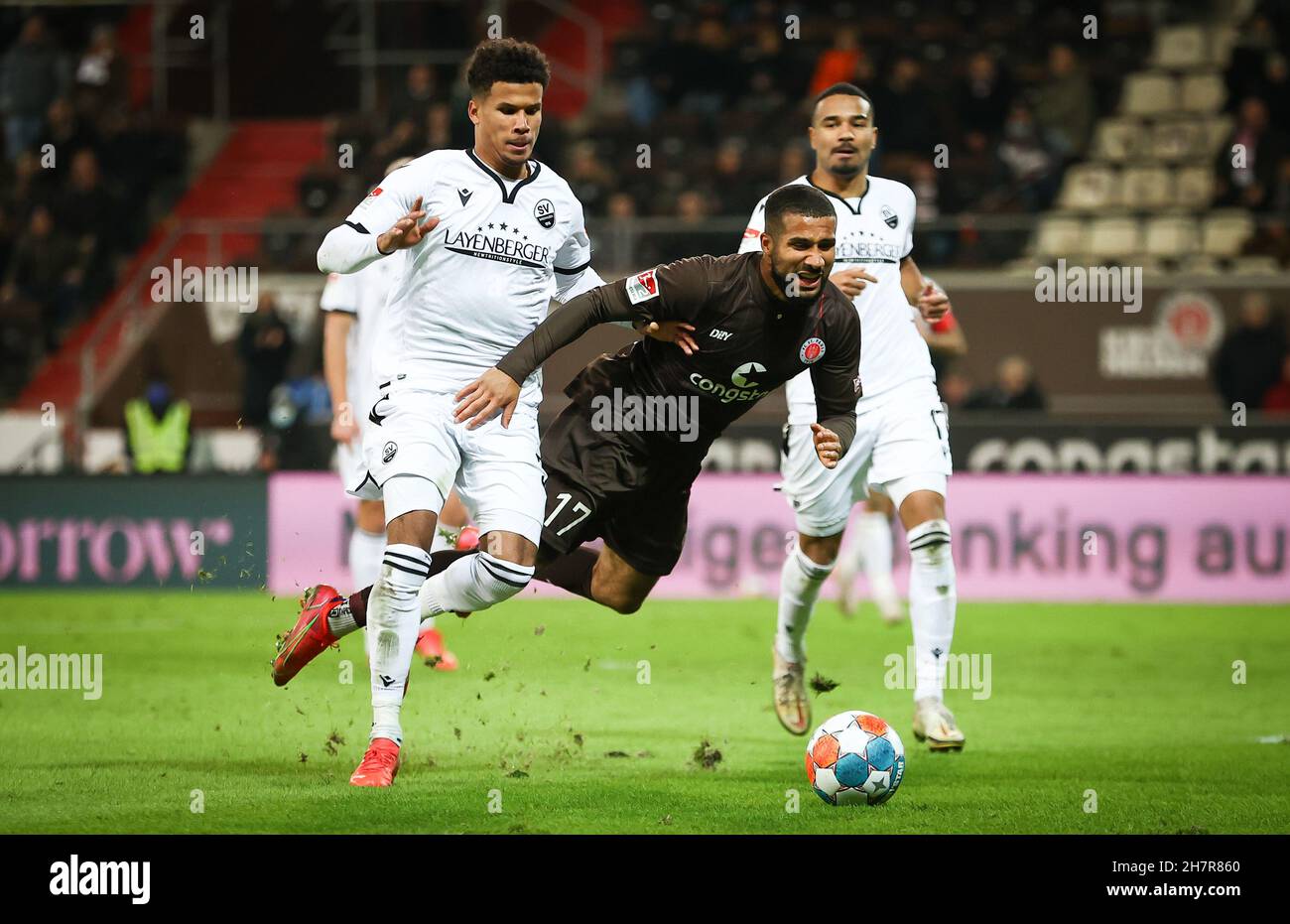 Hamburg, Germany. 24th Nov, 2021. Football: 2. Bundesliga, Matchday 13, FC St. Pauli - SV Sandhausen at Millerntor-Stadion. St. Pauli's Daniel-Kofi Kyereh (m) and Sandhausen's Chima Okoroji (l) fight for the ball. Credit: Christian Charisius/dpa - IMPORTANT NOTE: In accordance with the regulations of the DFL Deutsche Fußball Liga and/or the DFB Deutscher Fußball-Bund, it is prohibited to use or have used photographs taken in the stadium and/or of the match in the form of sequence pictures and/or video-like photo series./dpa/Alamy Live News Stock Photo