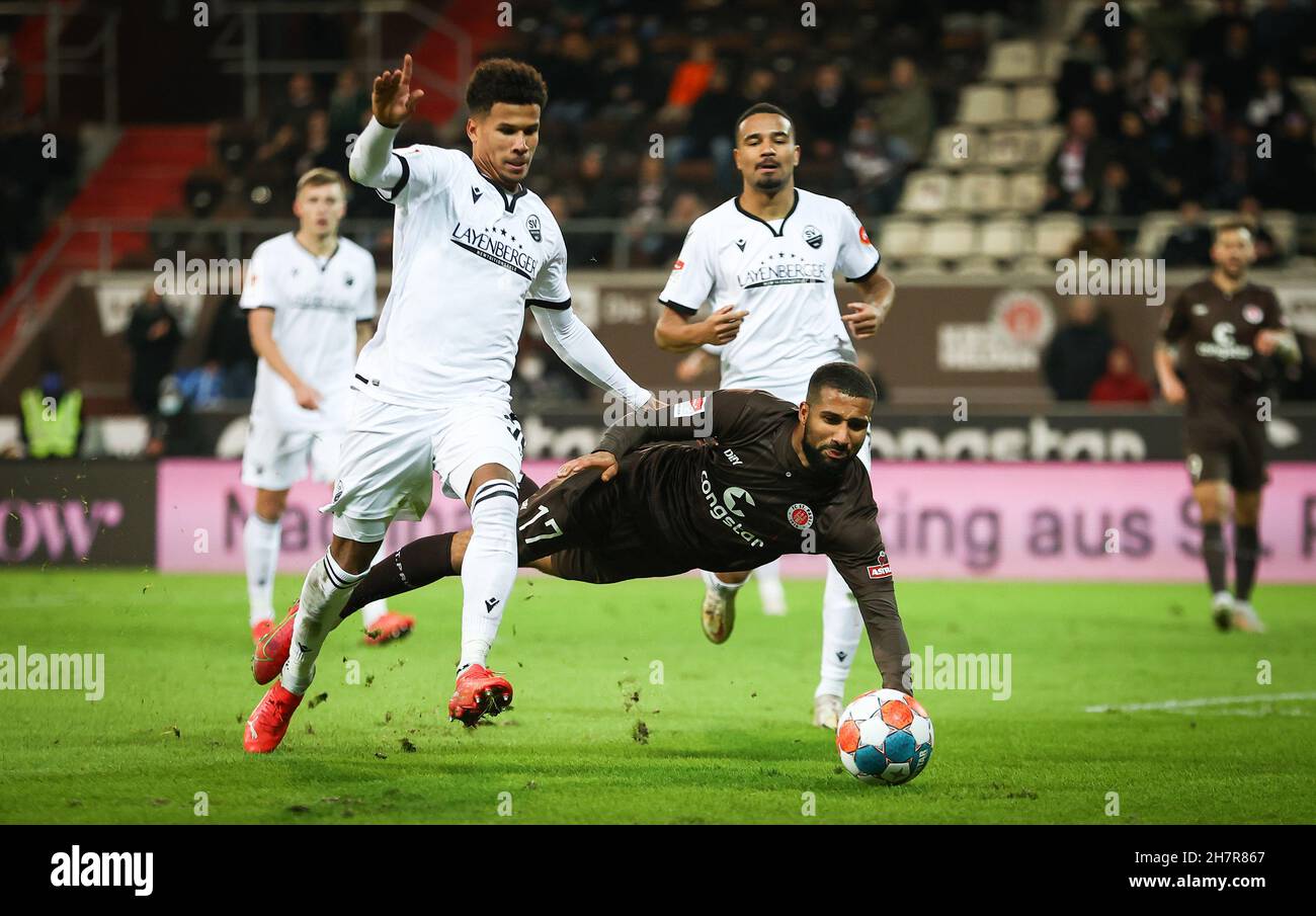 Hamburg, Germany. 24th Nov, 2021. Football: 2. Bundesliga, Matchday 13, FC St. Pauli - SV Sandhausen at Millerntor-Stadion. St. Pauli's Daniel-Kofi Kyereh (m) and Sandhausen's Chima Okoroji (l) fight for the ball. Credit: Christian Charisius/dpa - IMPORTANT NOTE: In accordance with the regulations of the DFL Deutsche Fußball Liga and/or the DFB Deutscher Fußball-Bund, it is prohibited to use or have used photographs taken in the stadium and/or of the match in the form of sequence pictures and/or video-like photo series./dpa/Alamy Live News Stock Photo