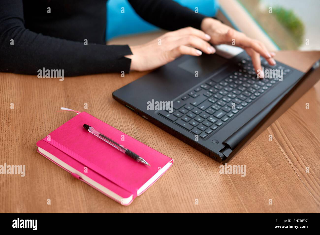 Cropped view of office worker sitting at table in cafe. Female hands type text on keypad on laptop Stock Photo