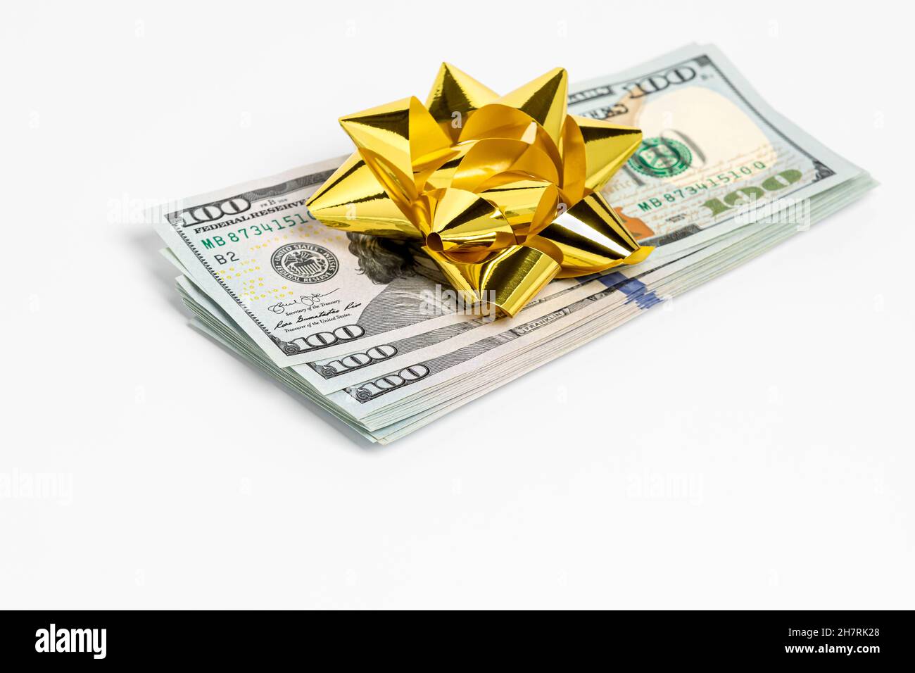 Cash gift of 100 dollar bills with gold bow. Gift tax, charitable donation and holiday present concept. Stock Photo