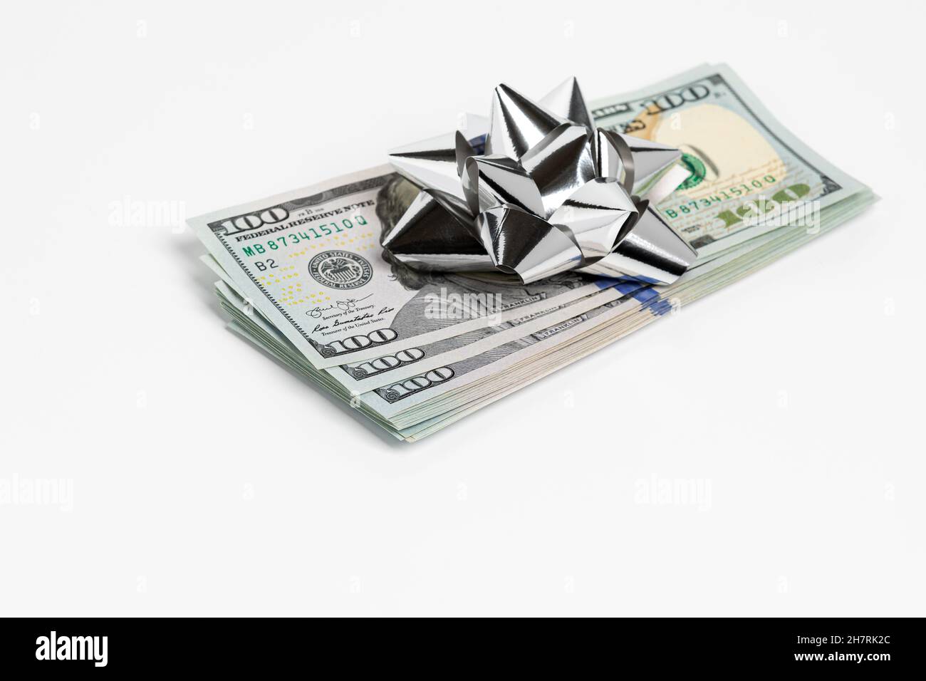 Cash gift of 100 dollar bills with silver bow. Gift tax, charitable donation and holiday present concept. Stock Photo