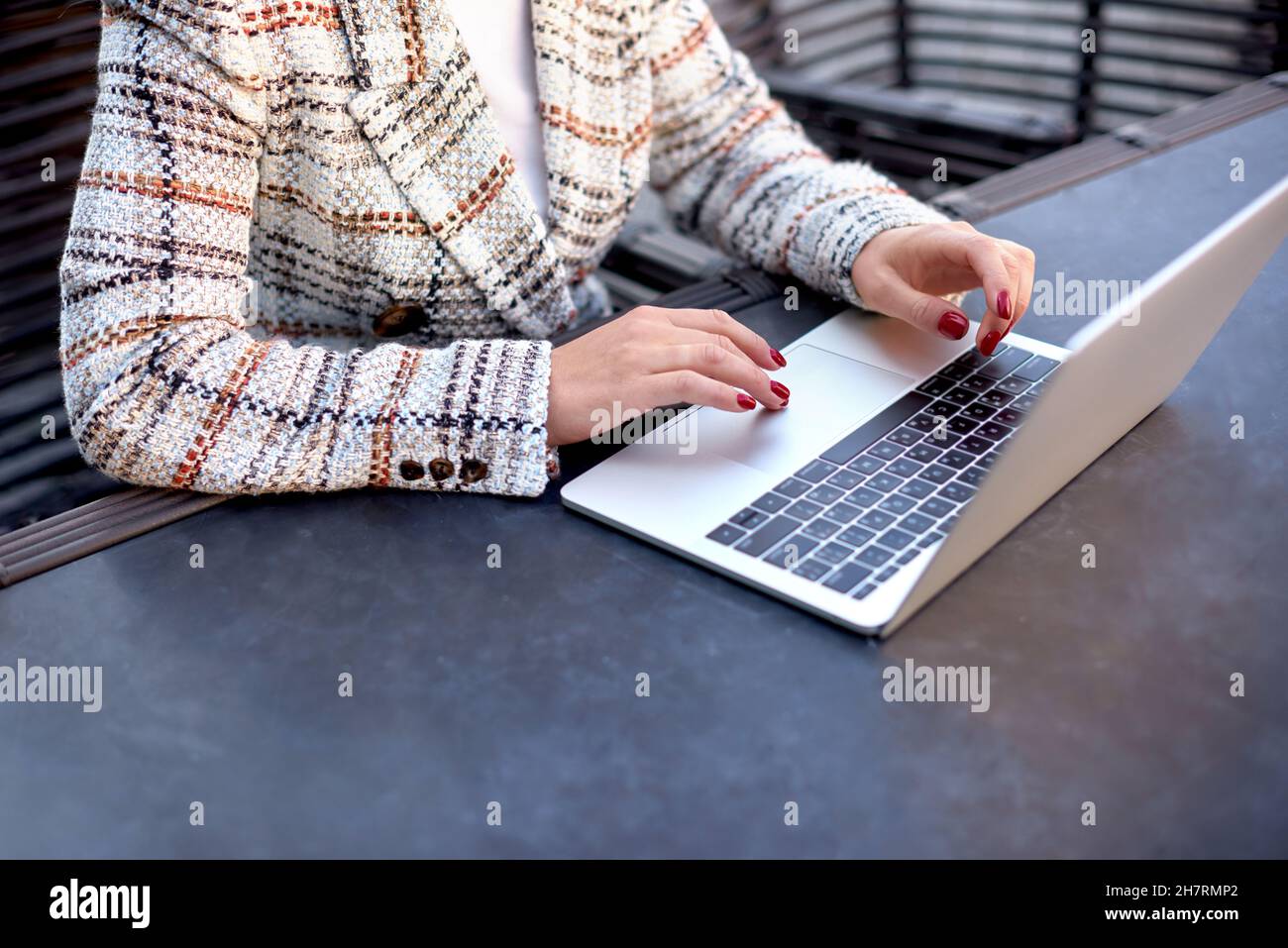 Cropped view of office worker sitting at table in cafe. Female hands type text on keypad on laptop Stock Photo