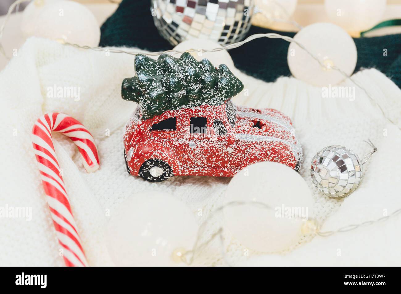 Red car with Christmas tree on white sweater, led lights. Christmas decoration on the snow Stock Photo