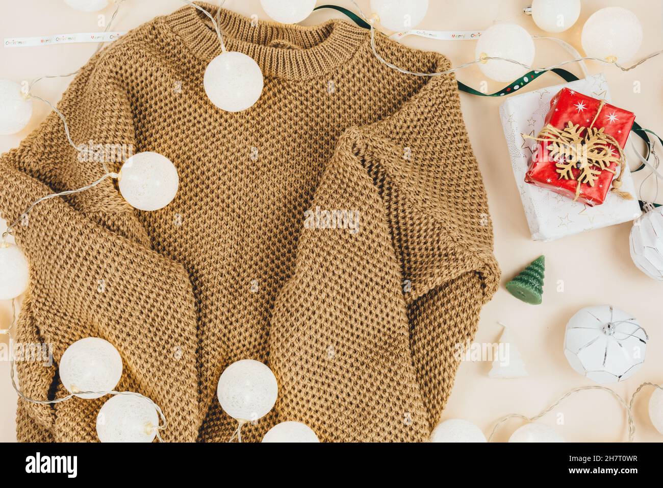 Brown knitted sweater and garlands, led lights. Women fashion winter clothes and accessories. New year and Christmas celebration mockup. Christmas Stock Photo