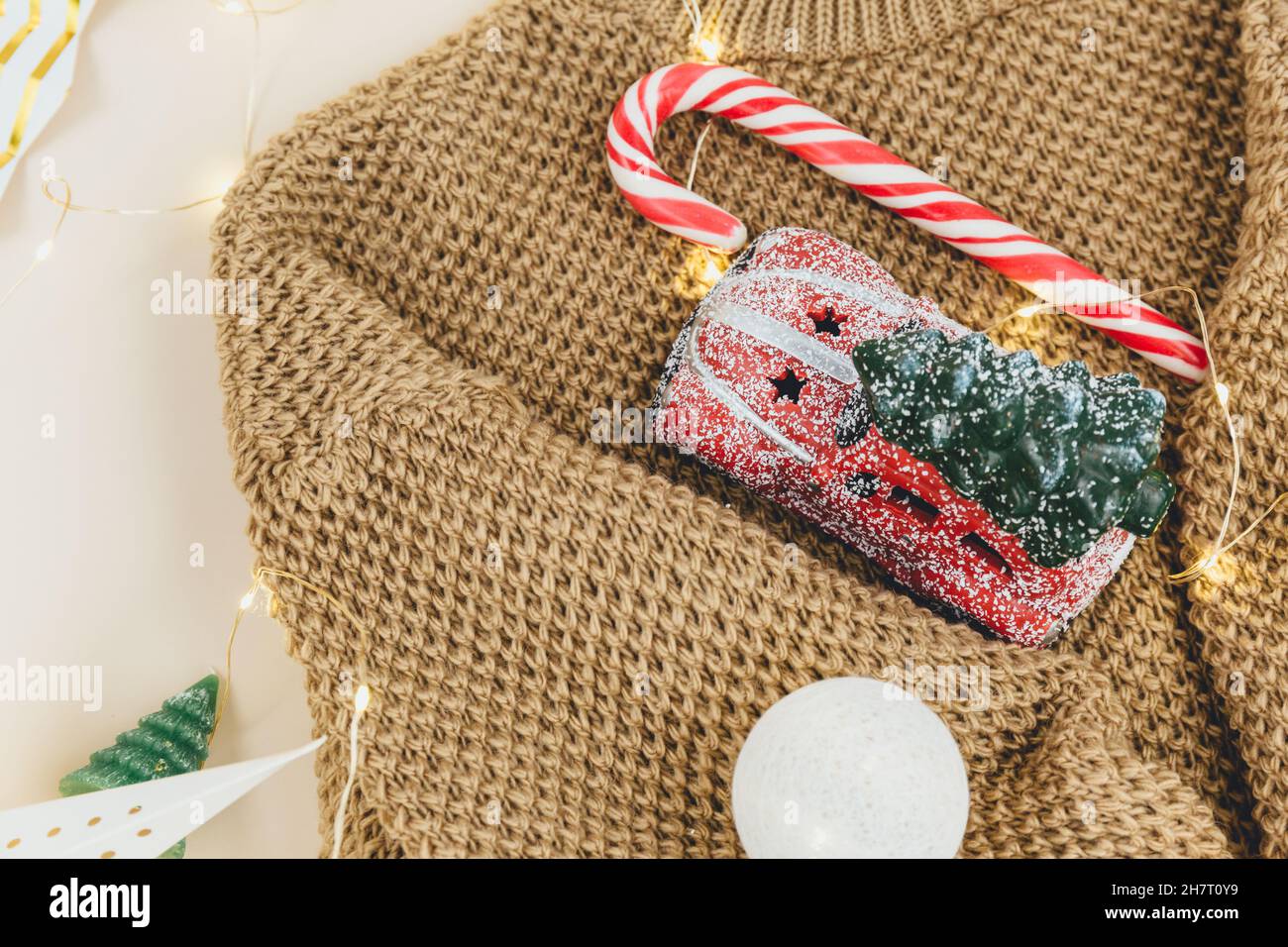 Brown knitted sweater and garlands, led lights. Women fashion winter clothes and accessories. New year and Christmas celebration mockup. Christmas bac Stock Photo