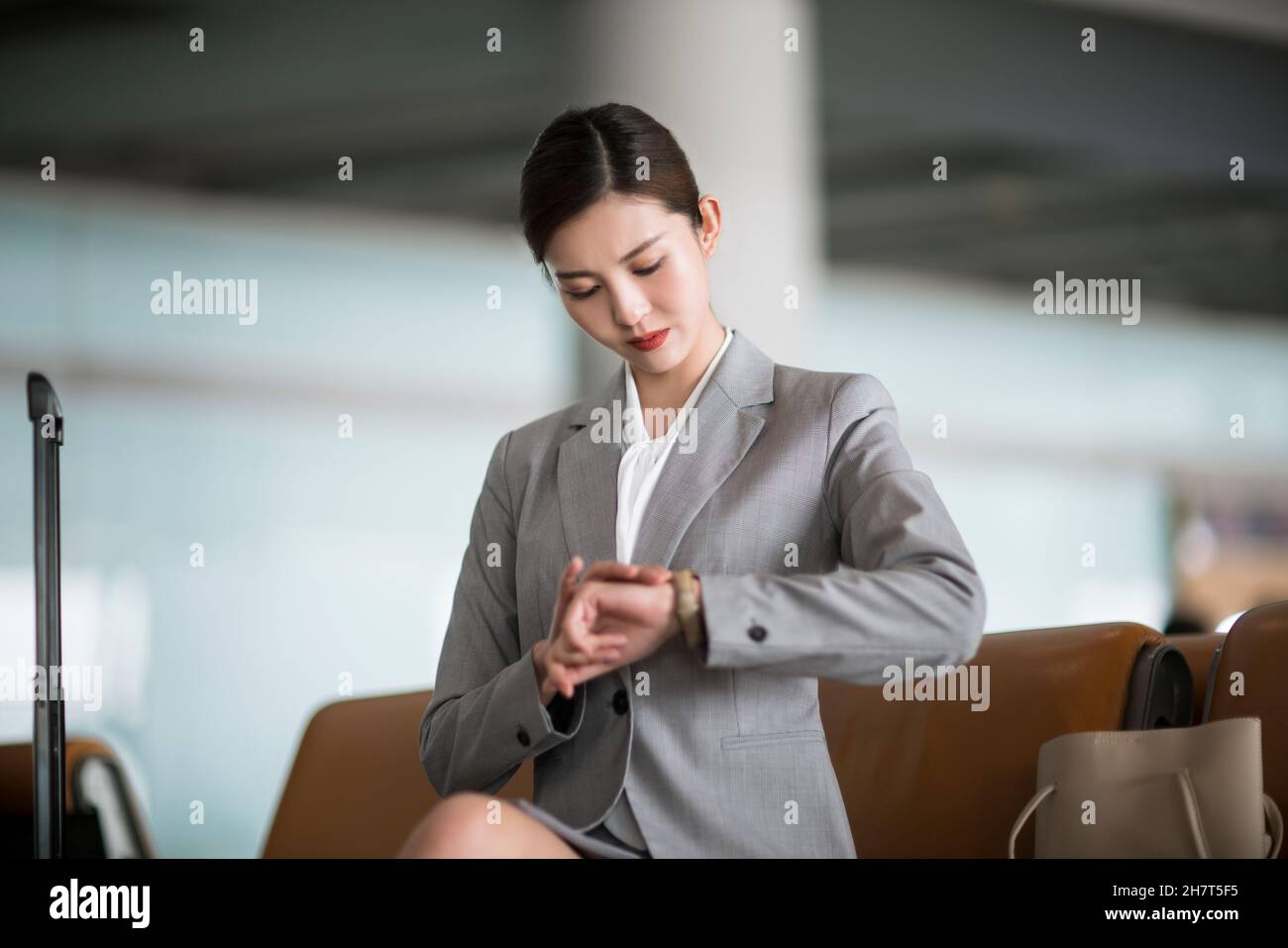 Young business woman looking at her watch in the airport lounge Stock Photo