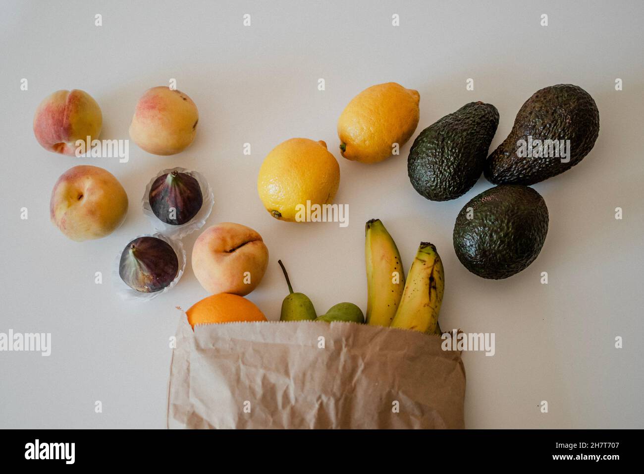 A variety of fruits in a crafted paper bag are lying on the table