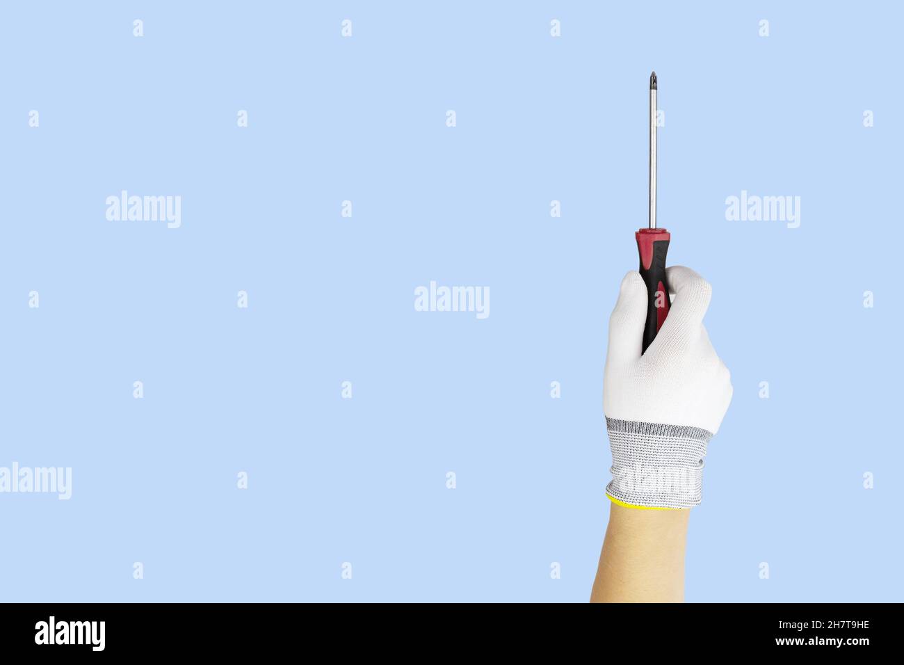 Gloved hands holding screwdriver construction tools. Work tools on blue background Stock Photo