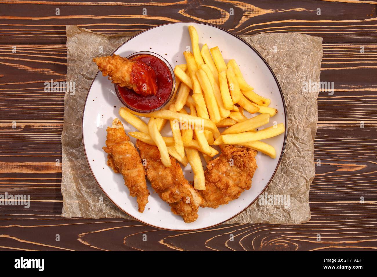 Plate with tasty french fries, deep fried chicken wings and tomato