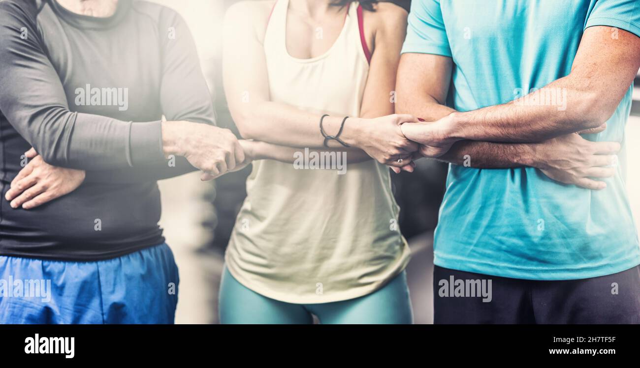 A team of two men and a woman in the middle in sportswear hold hands as a  symbol of team spirit and unity Stock Photo - Alamy