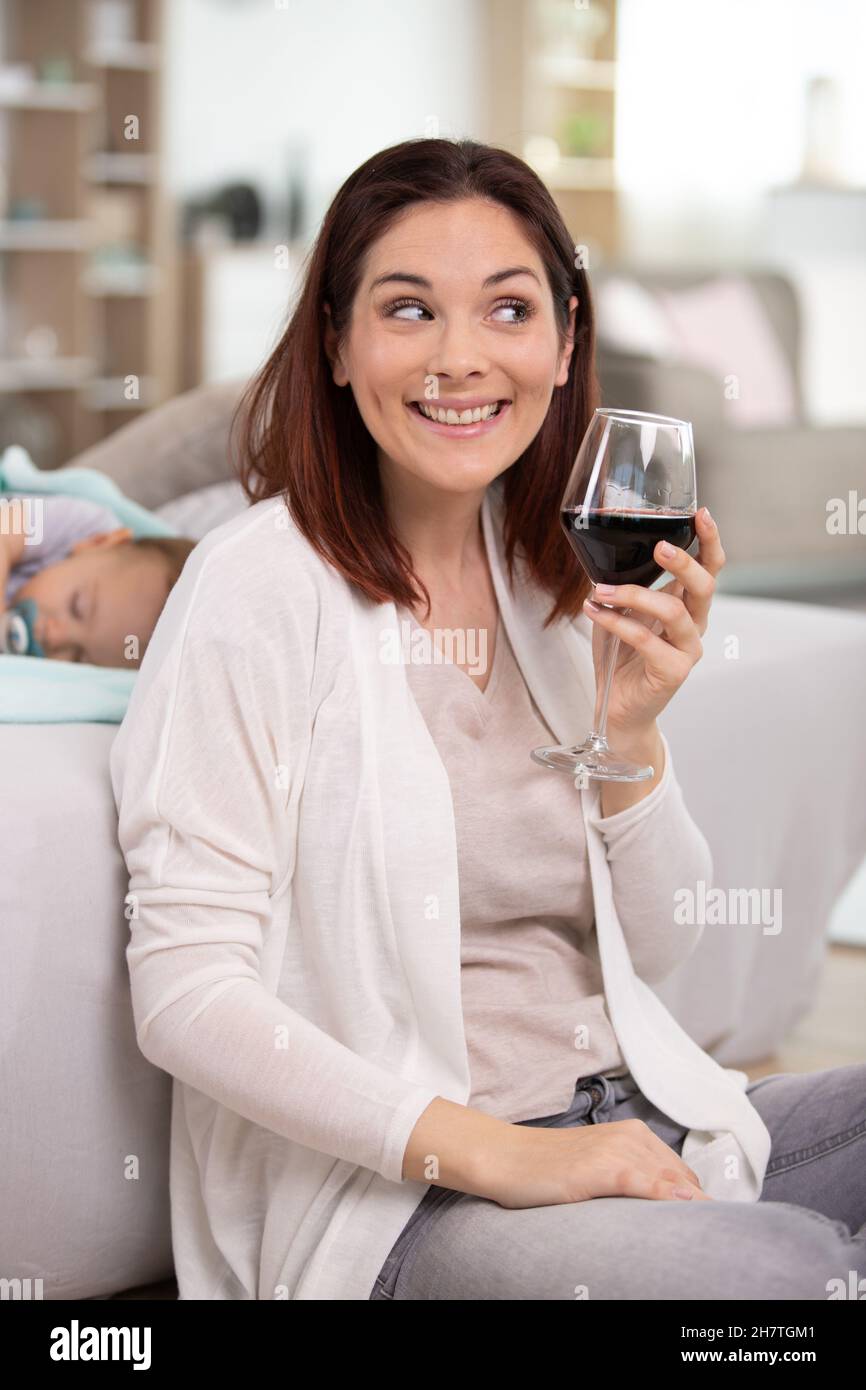 woman drinking alcohol with her sleeping baby Stock Photo
