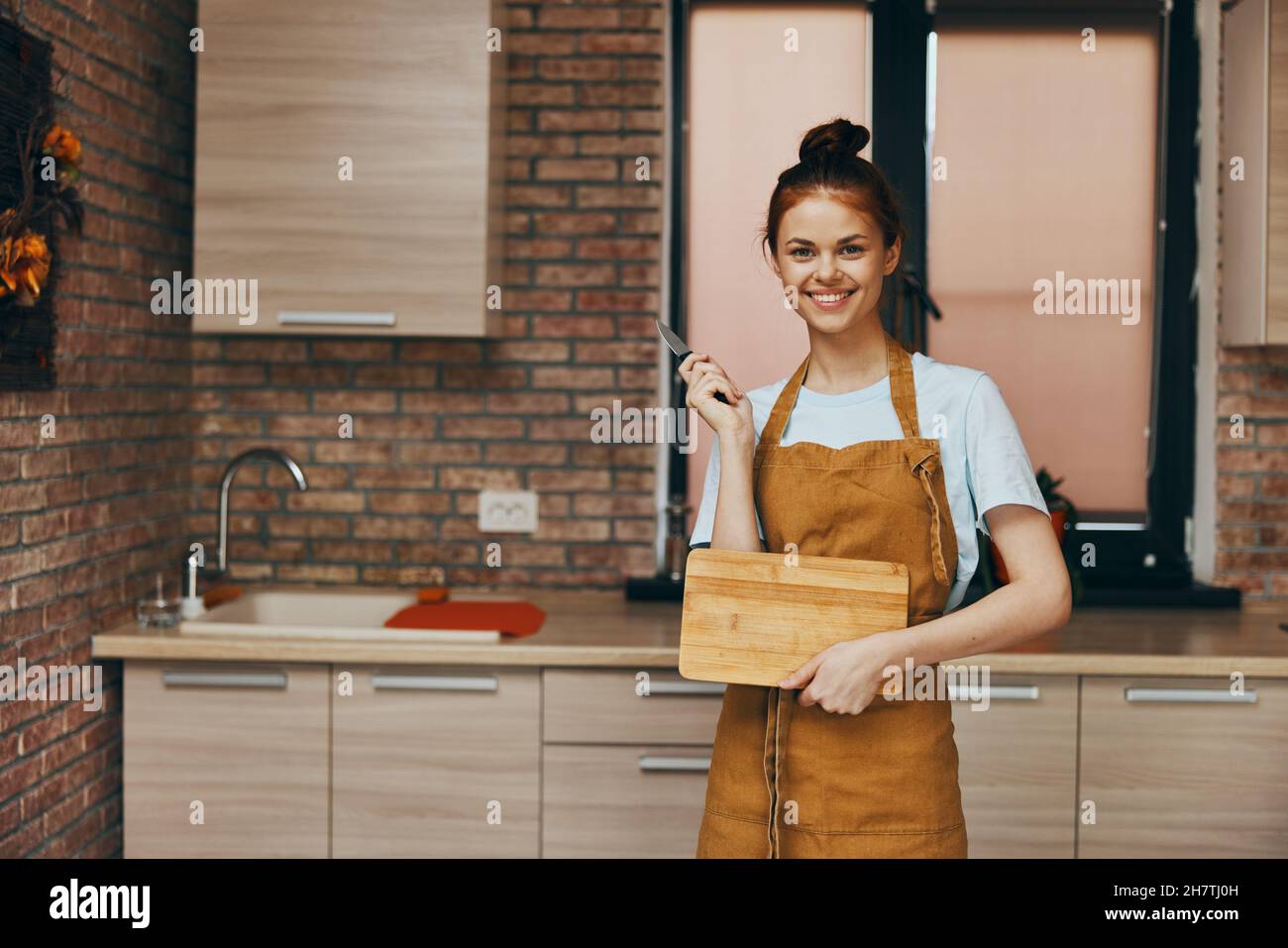cheerful woman houses in the kitchen cutting board with knife apartments unaltered Stock Photo