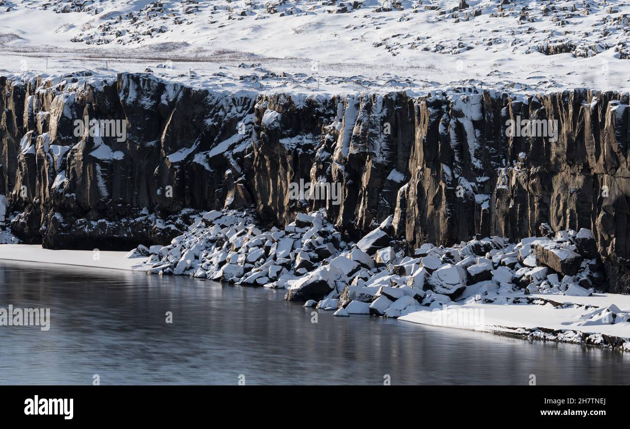 Boulder cubes under the cliffs with snow and river Stock Photo