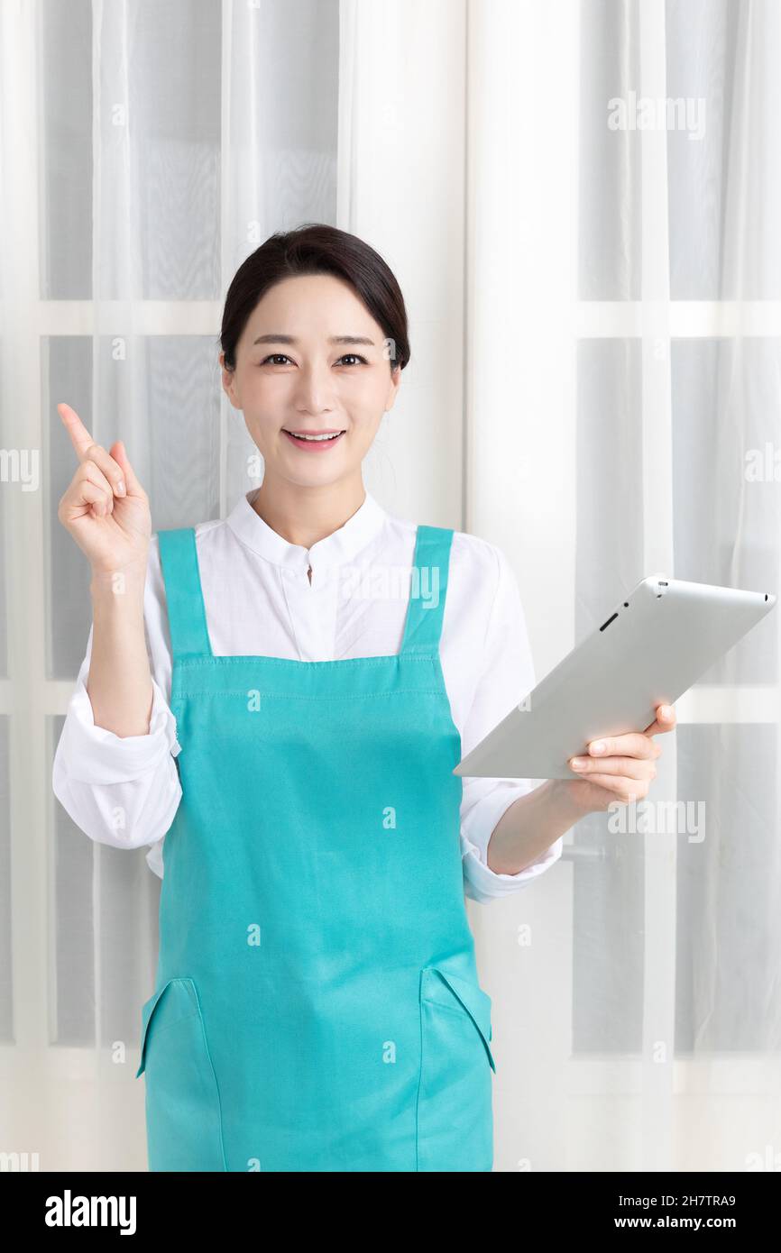 Asian woman wearing white shirt and apron, professional home cleaning