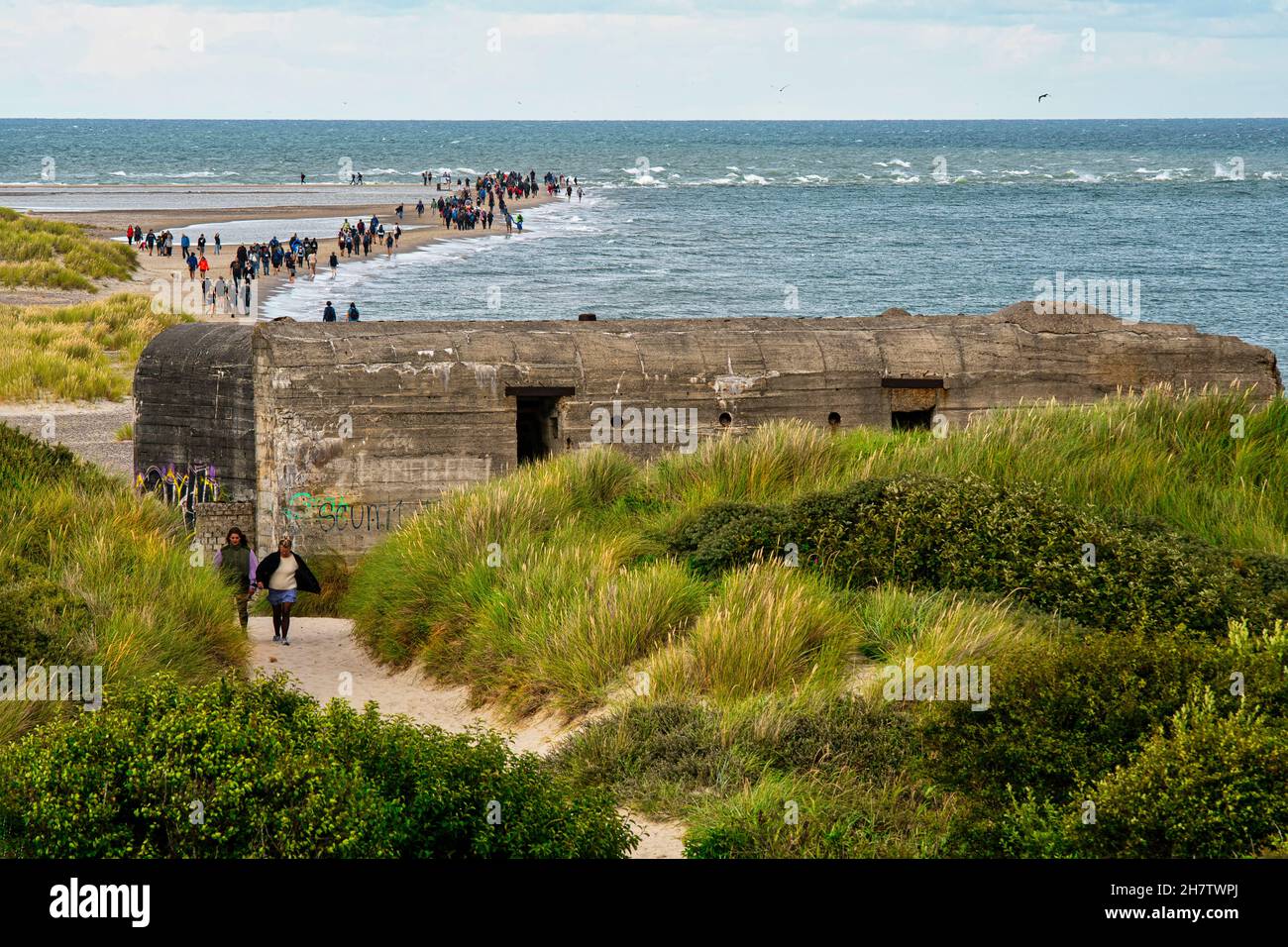 Tourists along the sandy peninsula of Grenen where the Baltic Sea meet the North Sea. In the foreground the ruins of bunker. Frederikshavn, Denmark Stock Photo