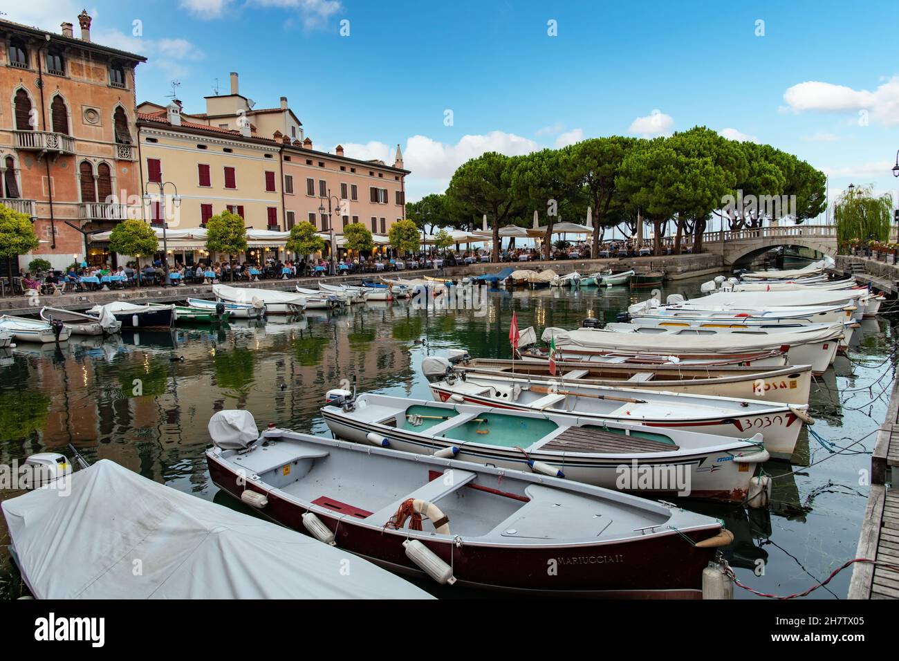 Desenzano, Italy-October 2021; View over the inner harbor Porto Vecchio with numerous small fishing boats and line with traditional colorful buildings Stock Photo