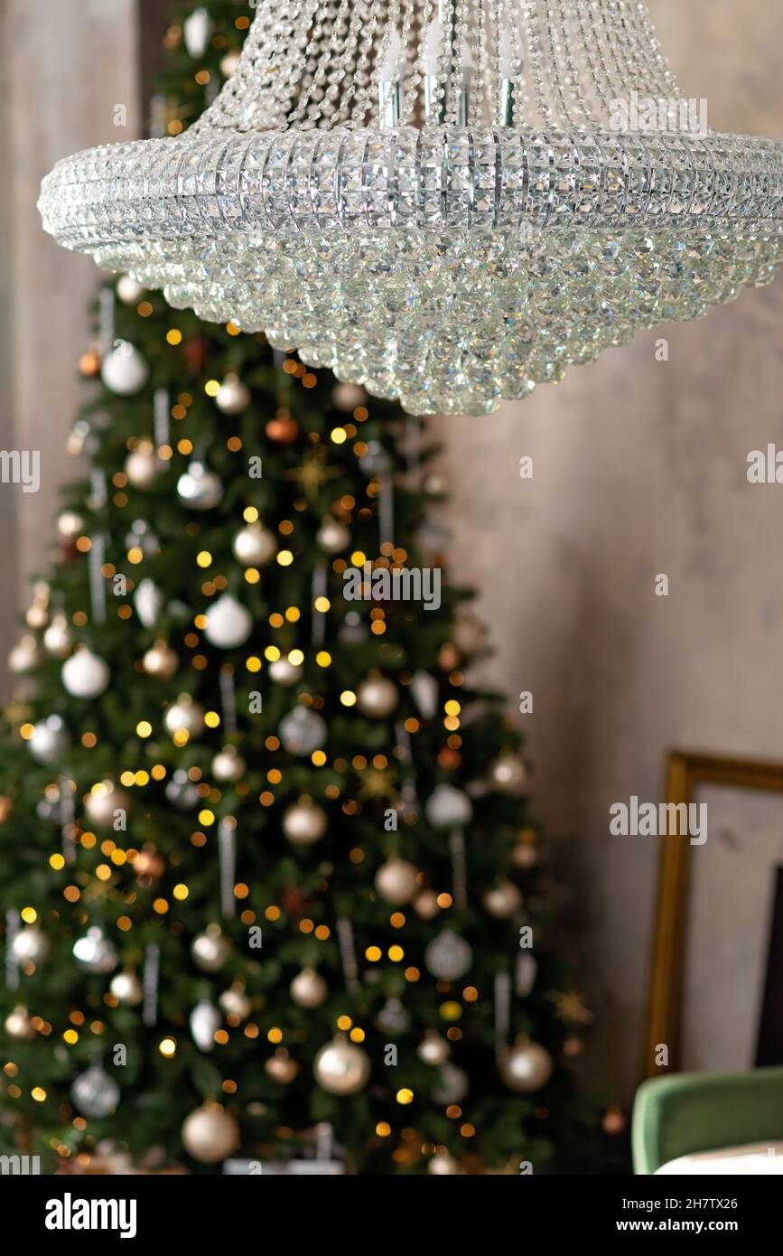 New year background. Christmas loft room interior. Lighting, large crystal chandelier, candles and indoor hot lighting, garlands. Christmas tree. Soft Stock Photo