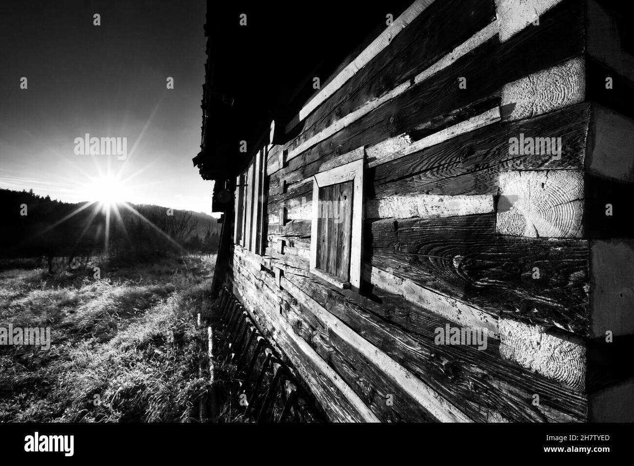 beautiful black and white wooden house, a gem of Slavic architecture, the corner of the house in view of the setting sun Stock Photo