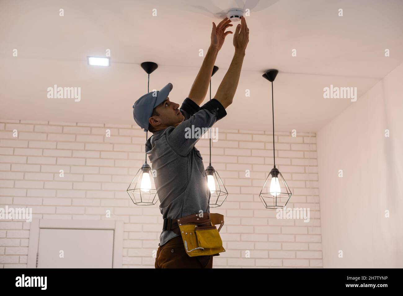 Handyman installing a smoke detector on the ceiling Stock Photo