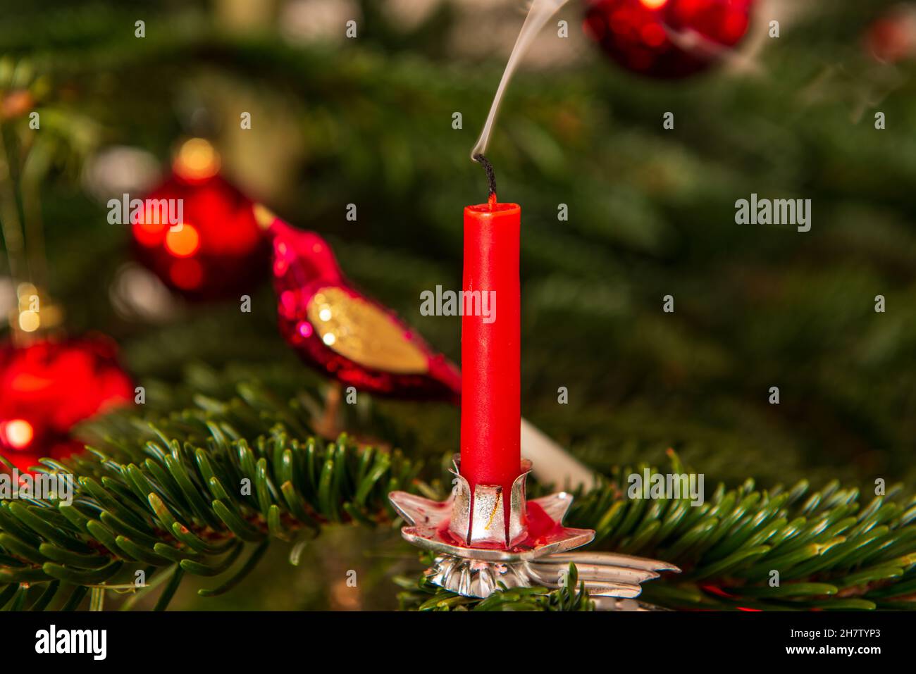 Erloschene rote Weihnachtskerze mit einer Rauchfahne an einem Weihnachtsbaum Stock Photo