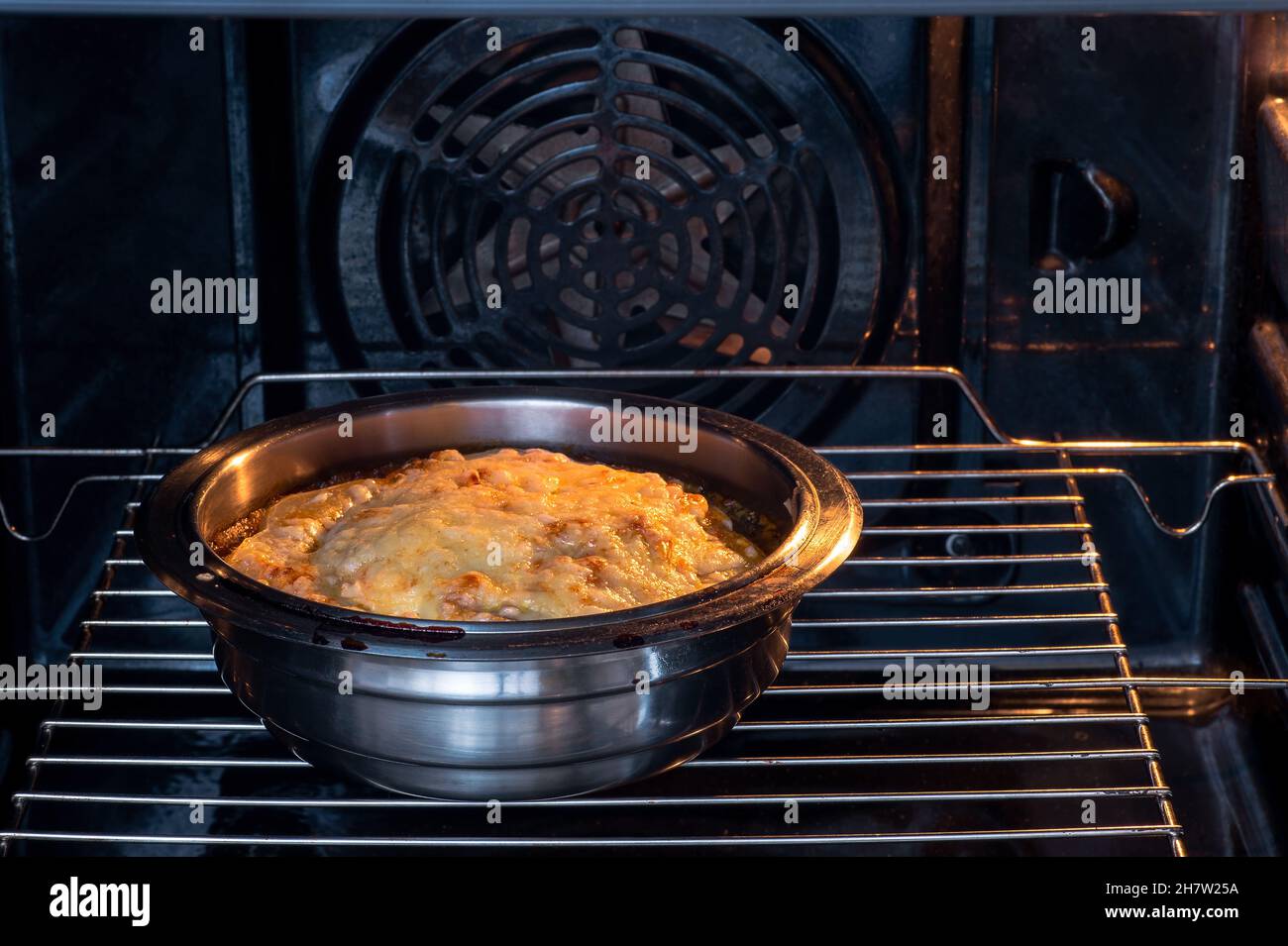 A dish in a metal bowl in the oven with a lush cheese brown crust. Abstract  concept of baking a dish of fish, vegetables in sauce. Background Stock  Photo - Alamy
