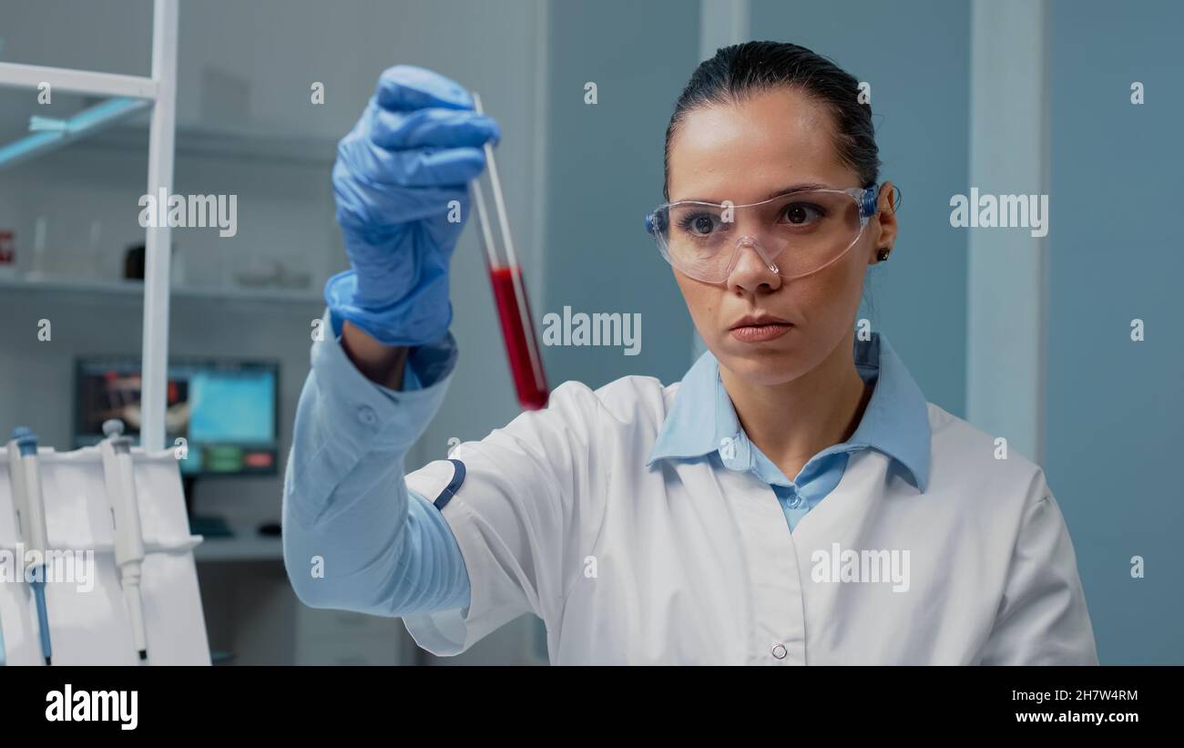 Microbiology doctor holding test tube filled with blood in laboratory