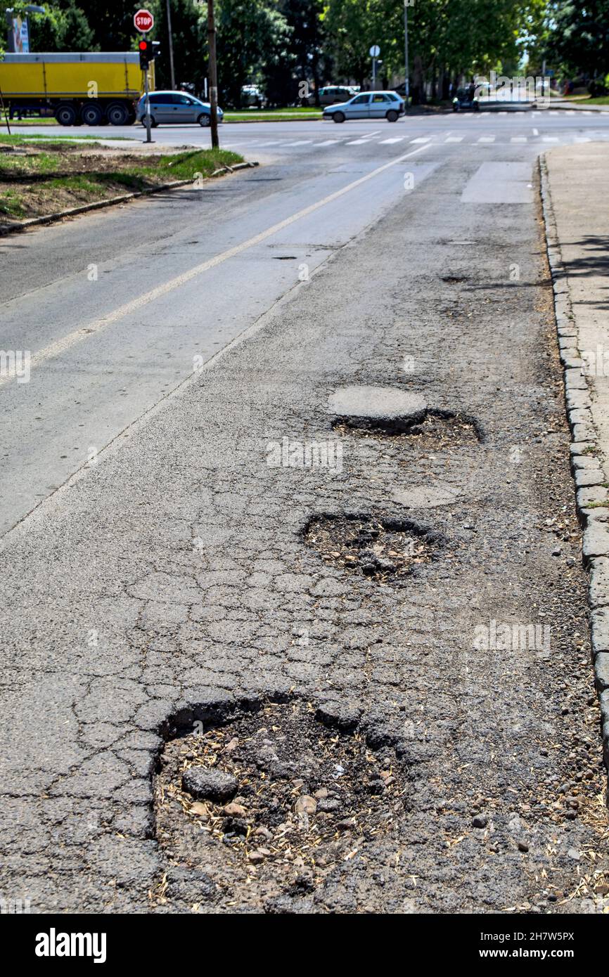 Three big holes on the asphalt road that are very dangerous when it rains. Then it is impossible to spot them from the car. Stock Photo