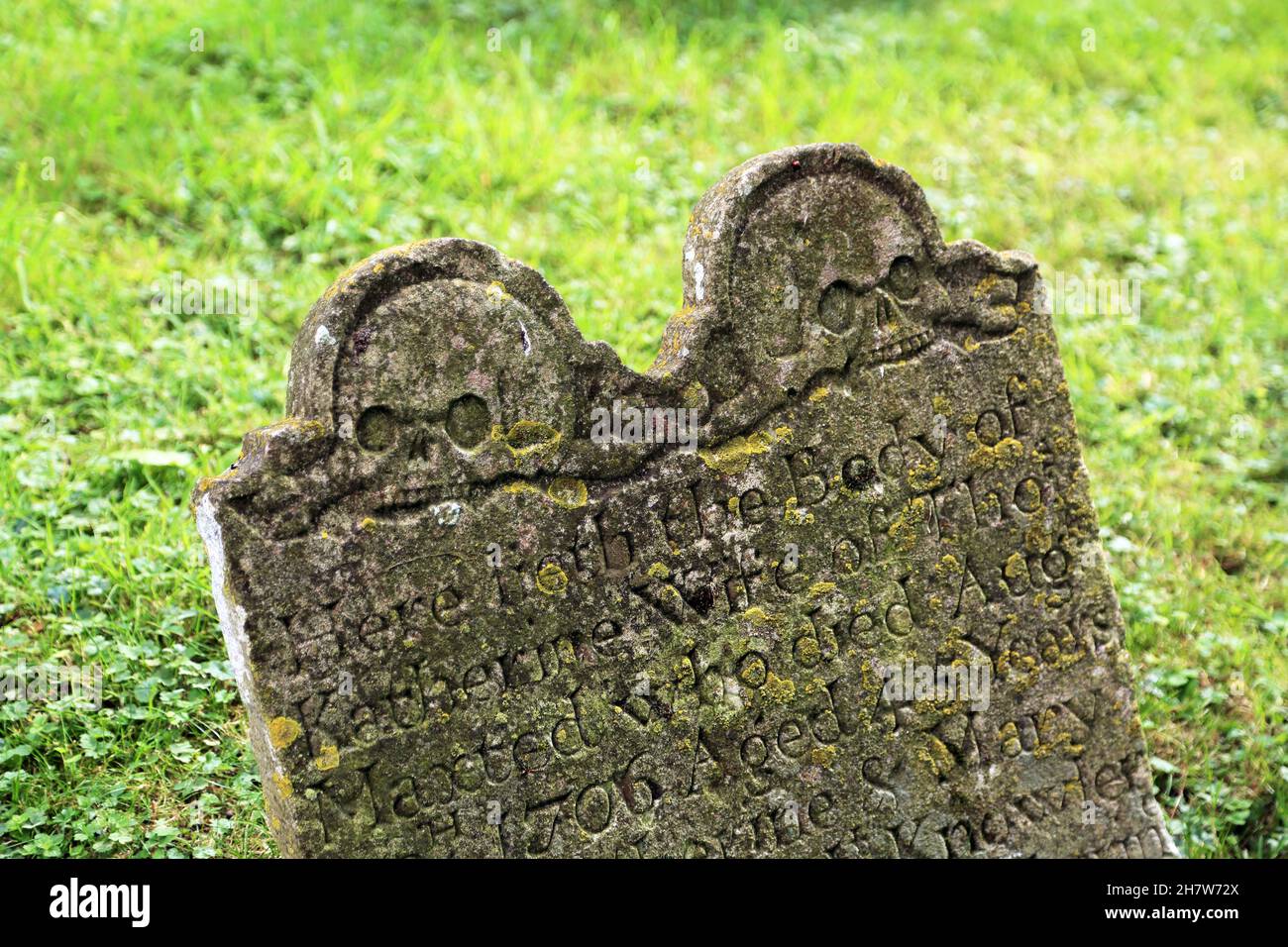 Ancient gravestone with sculls in the churchyard of St Mary the Virgin church on Stowting Hill, Stowting in the Kent Downs AONB, Ashford, Kent, Englan Stock Photo