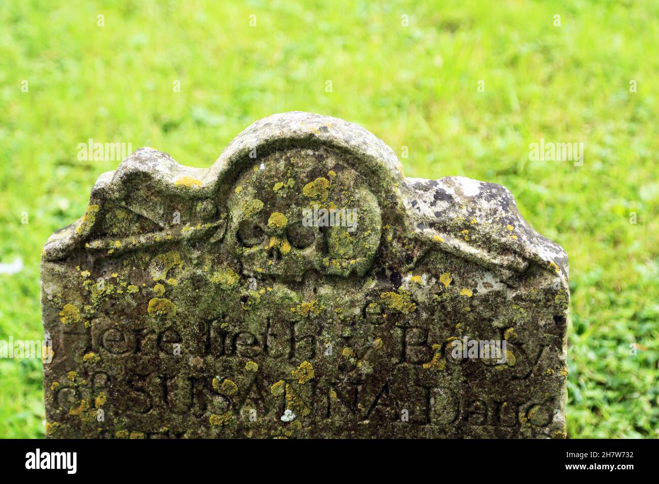 Ancient gravestone with sculls in the churchyard of St Mary the Virgin church on Stowting Hill, Stowting in the Kent Downs AONB, Ashford, Kent, Englan Stock Photo