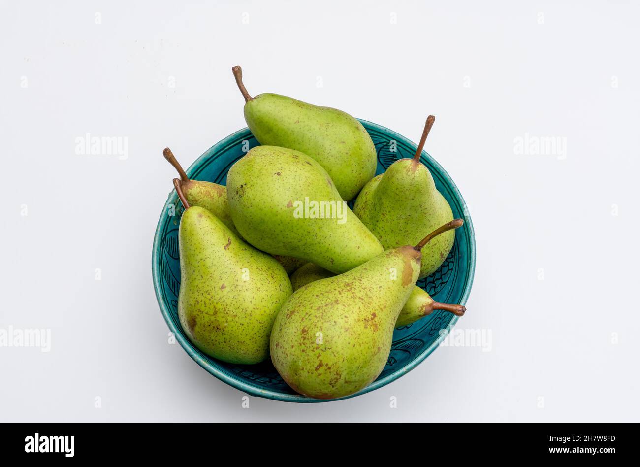 A bunch of ripe jucy pears with stalks in a blue clay bowl on a white background Stock Photo