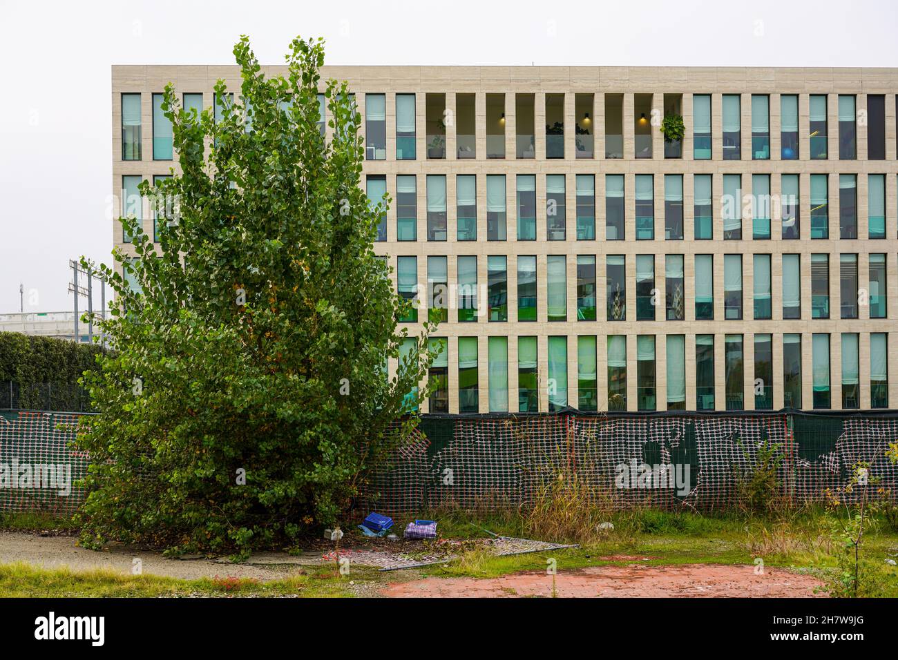 View of an office building behind a wall in Bologna. Ahead a tree. Stock Photo