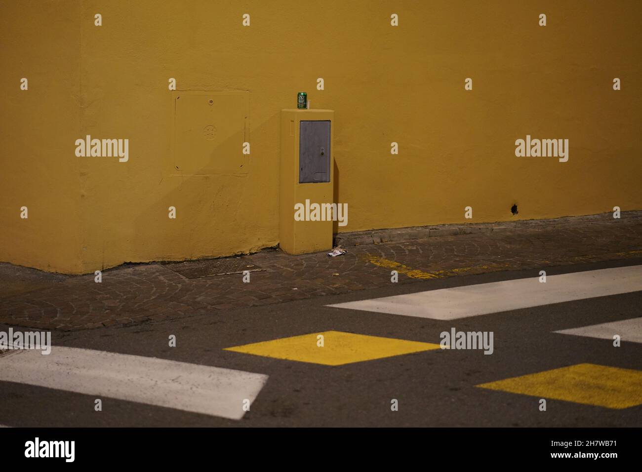 A dropped off drinks can in front of a yellow house wall on a street with yellow and white markings in Bologna, Italy. Stock Photo