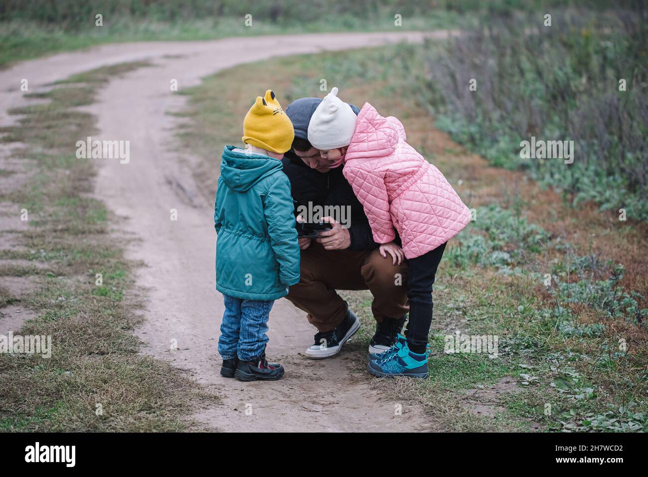 Happy family with two kids playing with drone in the field autumn time ...