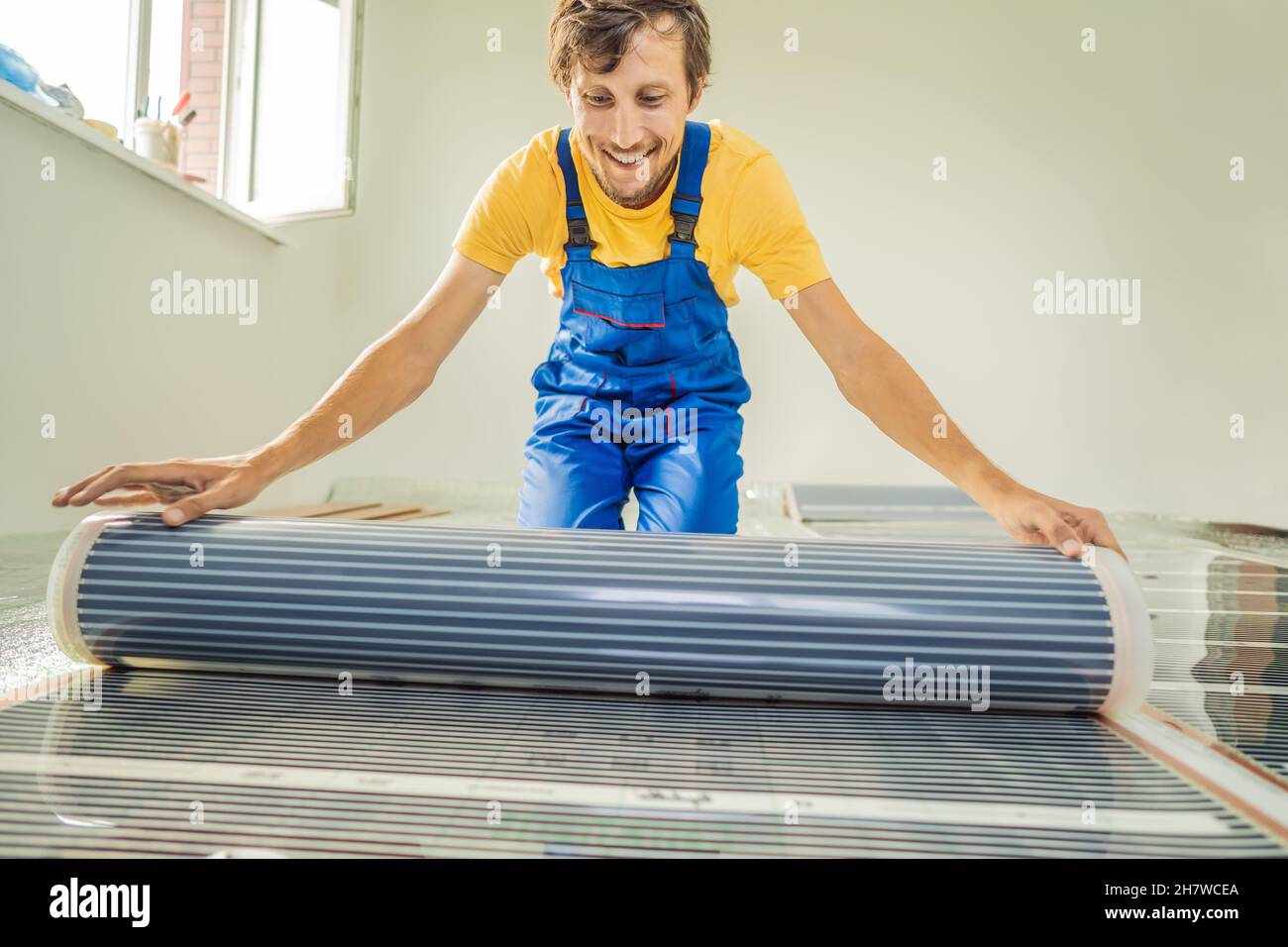 Master installs film warm floor in the room. Floor heating installation Stock Photo