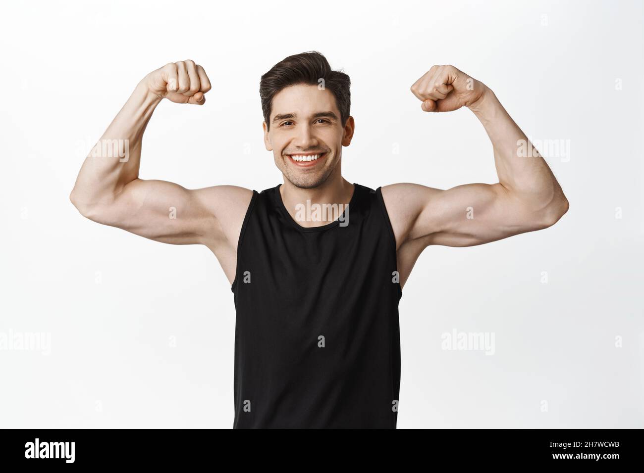 Sport And Gym Smiling Young Healthy Man Flexing Biceps Showing Strong Big Muscles And Fit Body