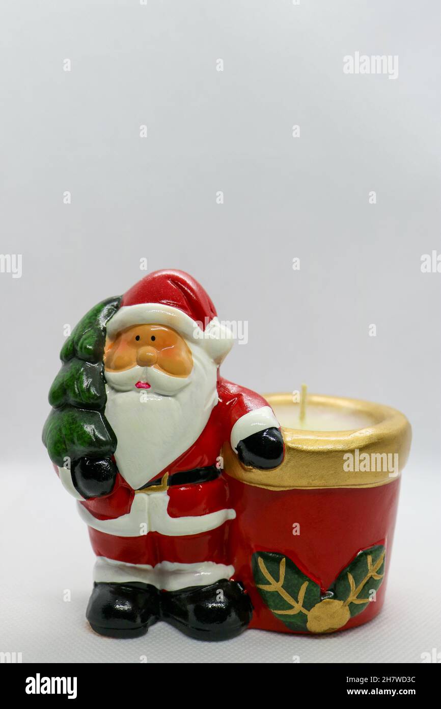 Santa Claus with red body, green Christmas tree and candle, Santa Claus  ceramic figure on white background, Christmas  decoration, New Year card Stock Photo