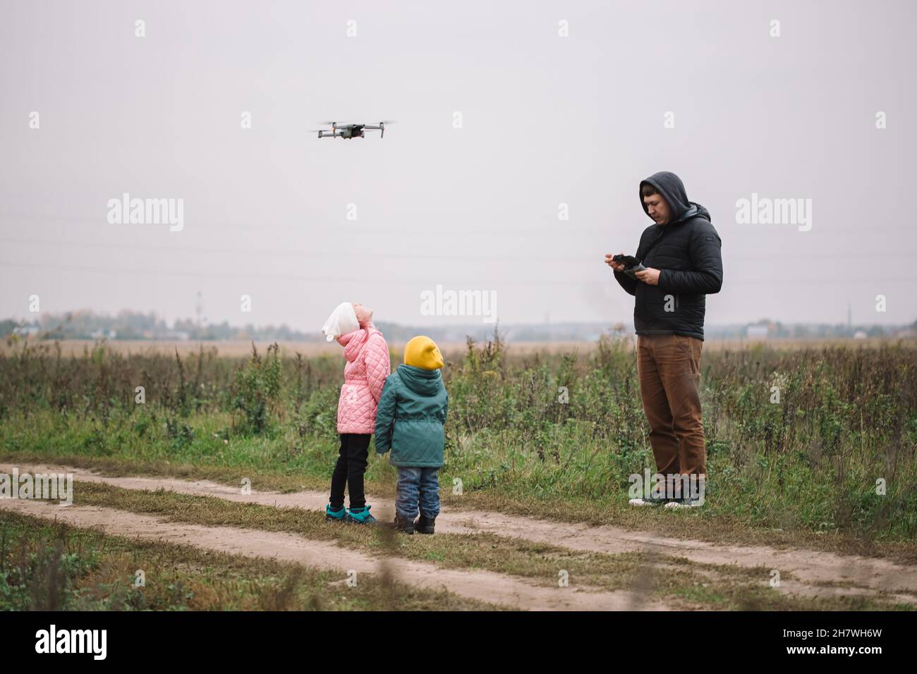Happy family with two kids playing with drone in the field autumn time ...