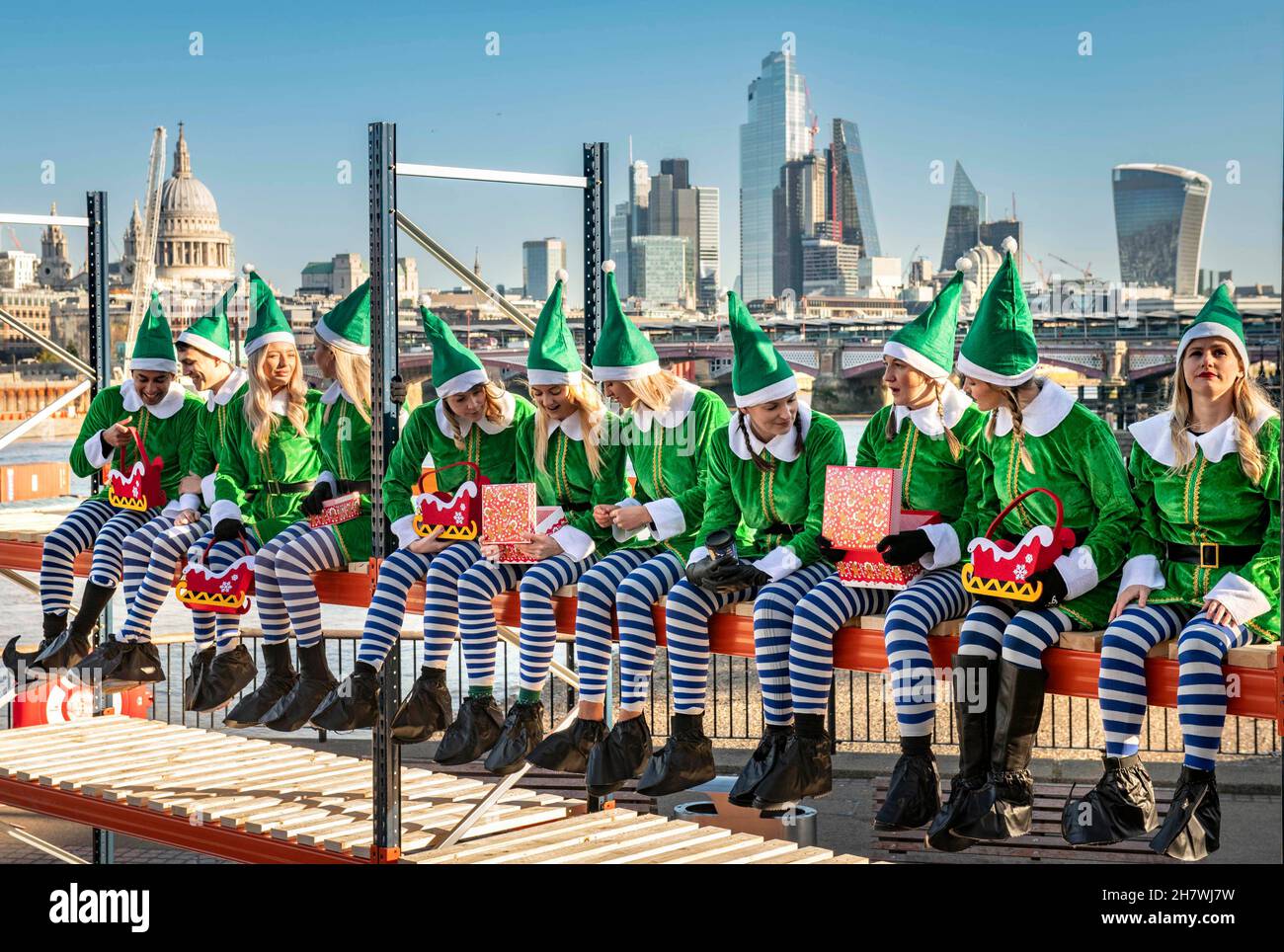 EDITORIAL USE ONLY Eleven 'elves’ sit side-by-side on a 4-metre tall unit from company, BiGDUG to recreate the well-known 'Lunch atop a Skyscraper’ photograph, ahead of Christmas, London. Picture date: Thursday November 25, 2021. Stock Photo