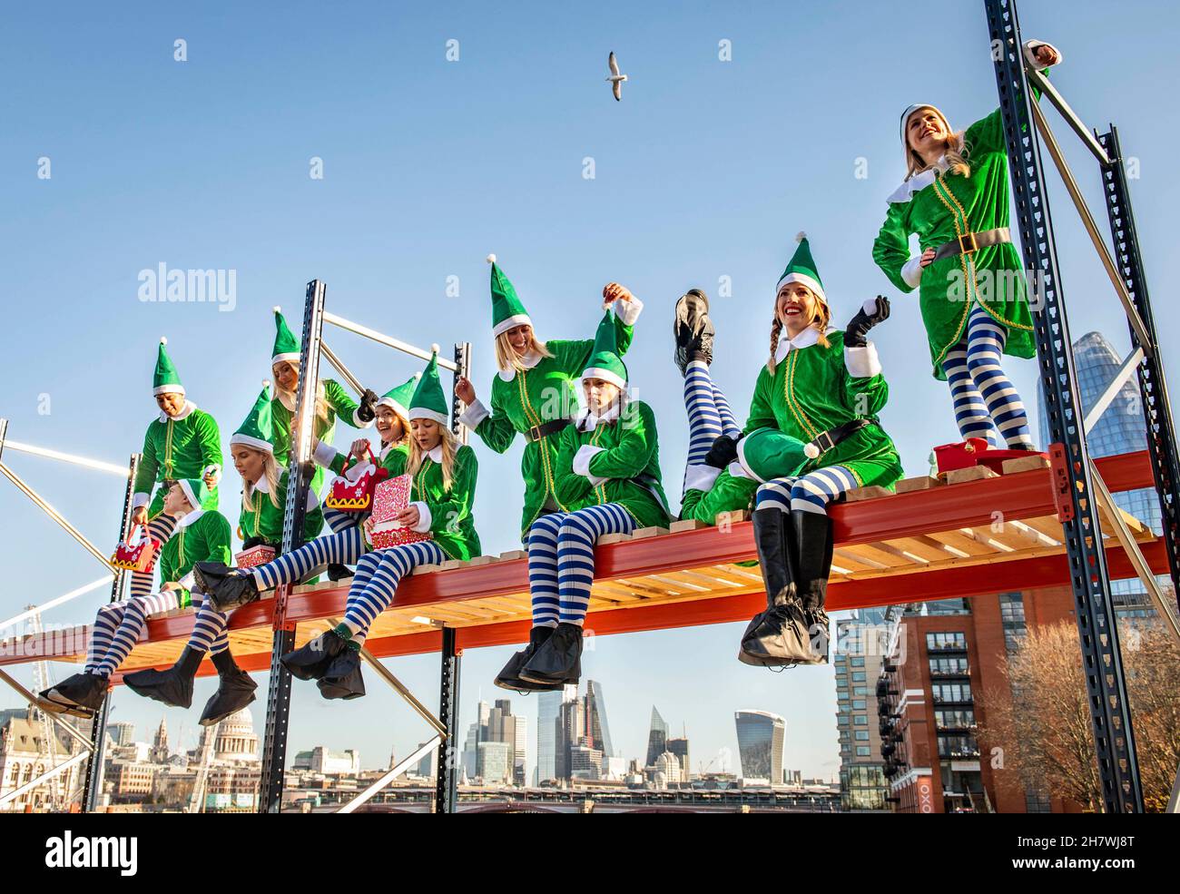 EDITORIAL USE ONLY Eleven 'elves’ sit side-by-side on a 4-metre tall unit from company, BiGDUG to recreate the well-known 'Lunch atop a Skyscraper’ photograph, ahead of Christmas, London. Picture date: Thursday November 25, 2021. Stock Photo