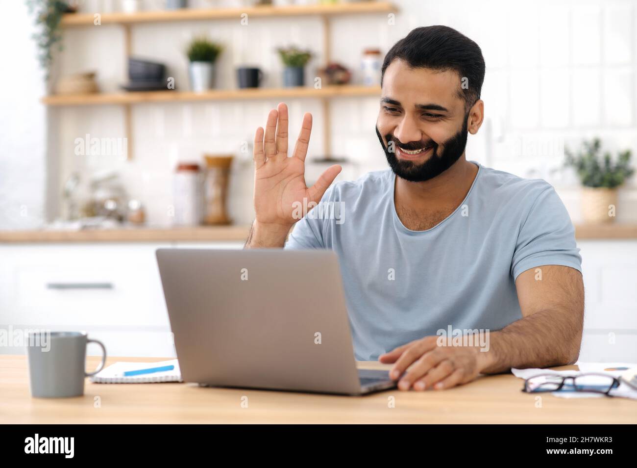 Video conference, distant communication. Positive Indian man, freelancer, designer or manager, work from home, using a laptop for communication via video call, talking to a colleague or friend, smiles Stock Photo