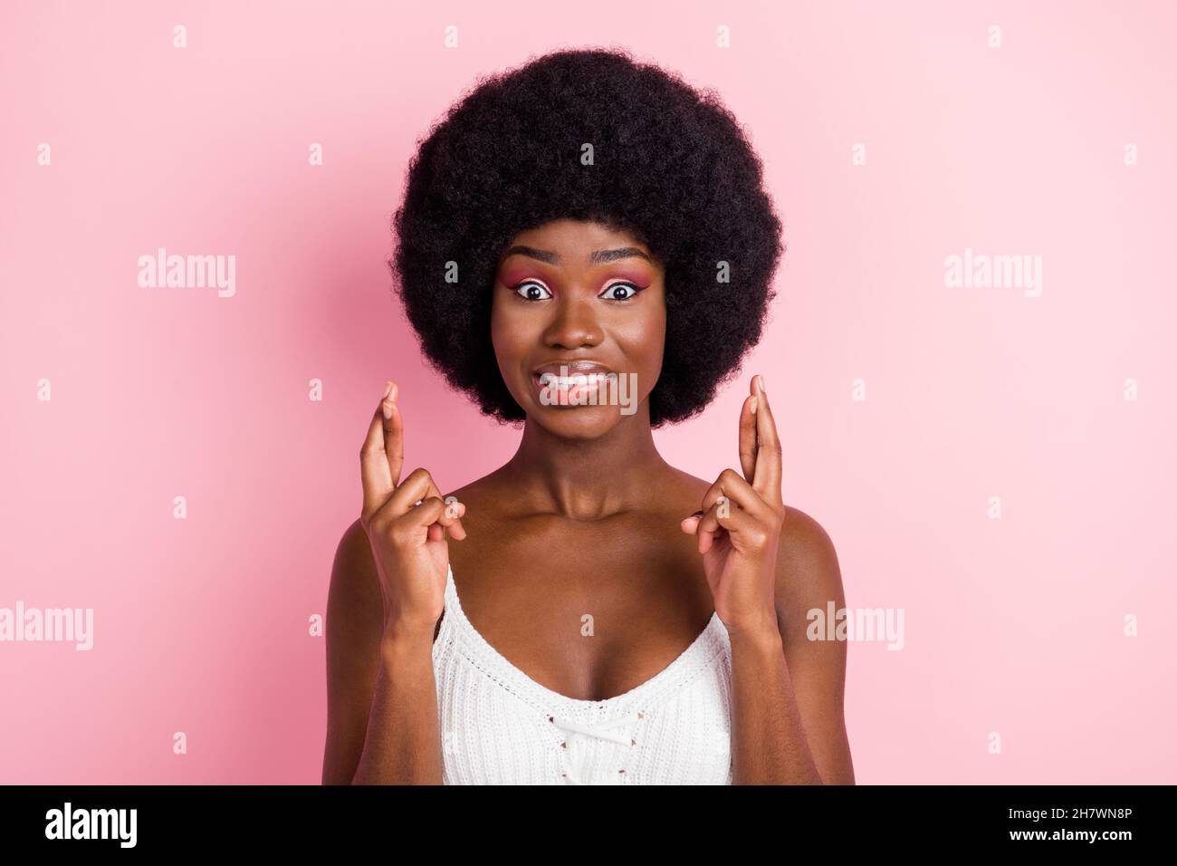 Photo portrait curly girl in white top biting lip crossed fingers hope isolated pastel pink color background Stock Photo