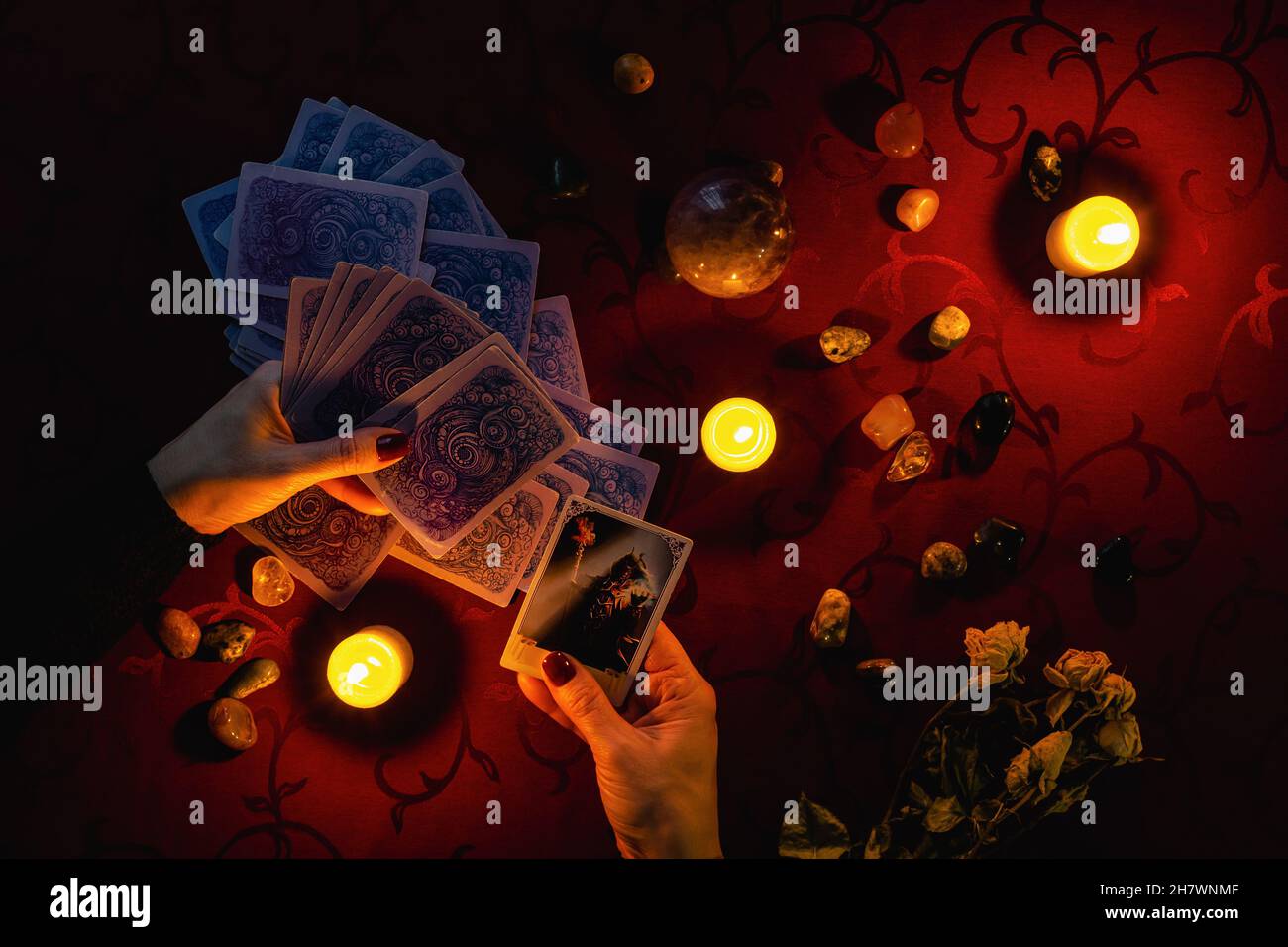 Minsk, Belarus - November 2021: A fortune teller makes a Tarot layout and holds a Devil card in her hand. Magic and occultism. Stock Photo