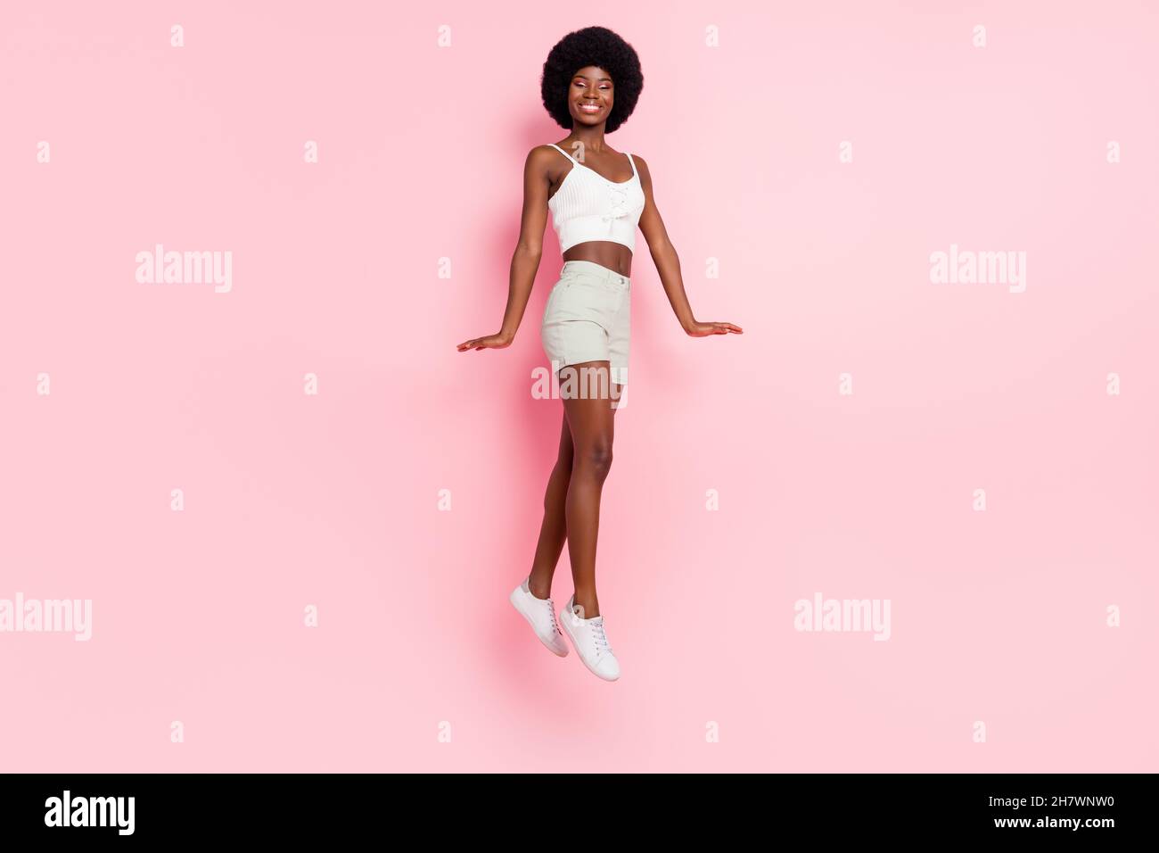 Photo of shy adorable cheerful lady jump wear cropped top shorts sneakers isolated pink color background Stock Photo