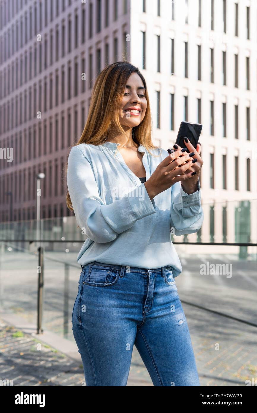 Business young latin woman holding her smart phone while smiling ...