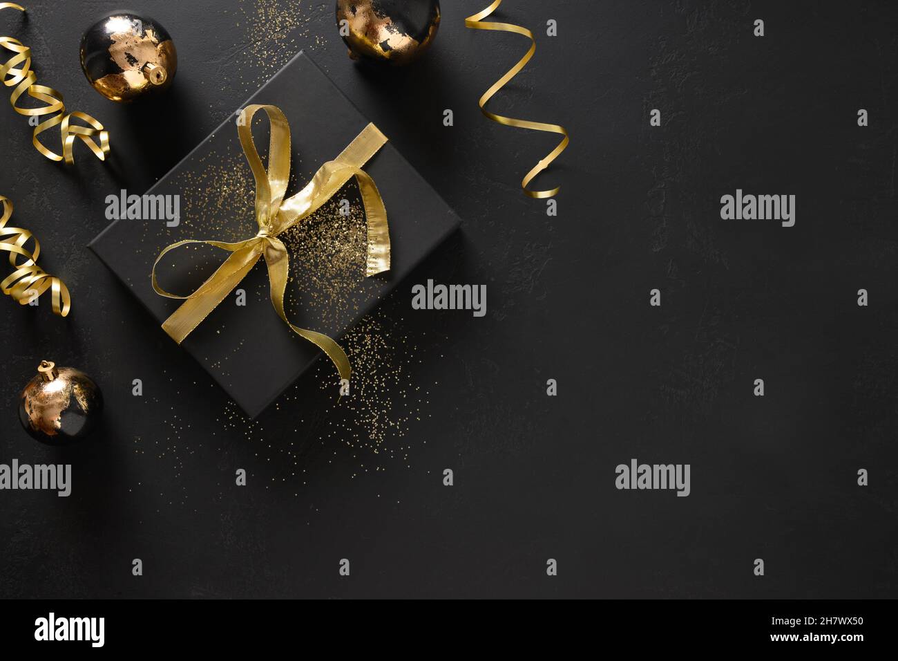 Gold and black gift and baubles on a black background with Christmas ...
