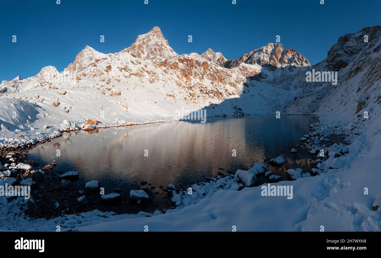 A high-mountain lake against a background of snow-covered mountain peaks in the early morning in the Karachay-Cherkessia Republic Stock Photo